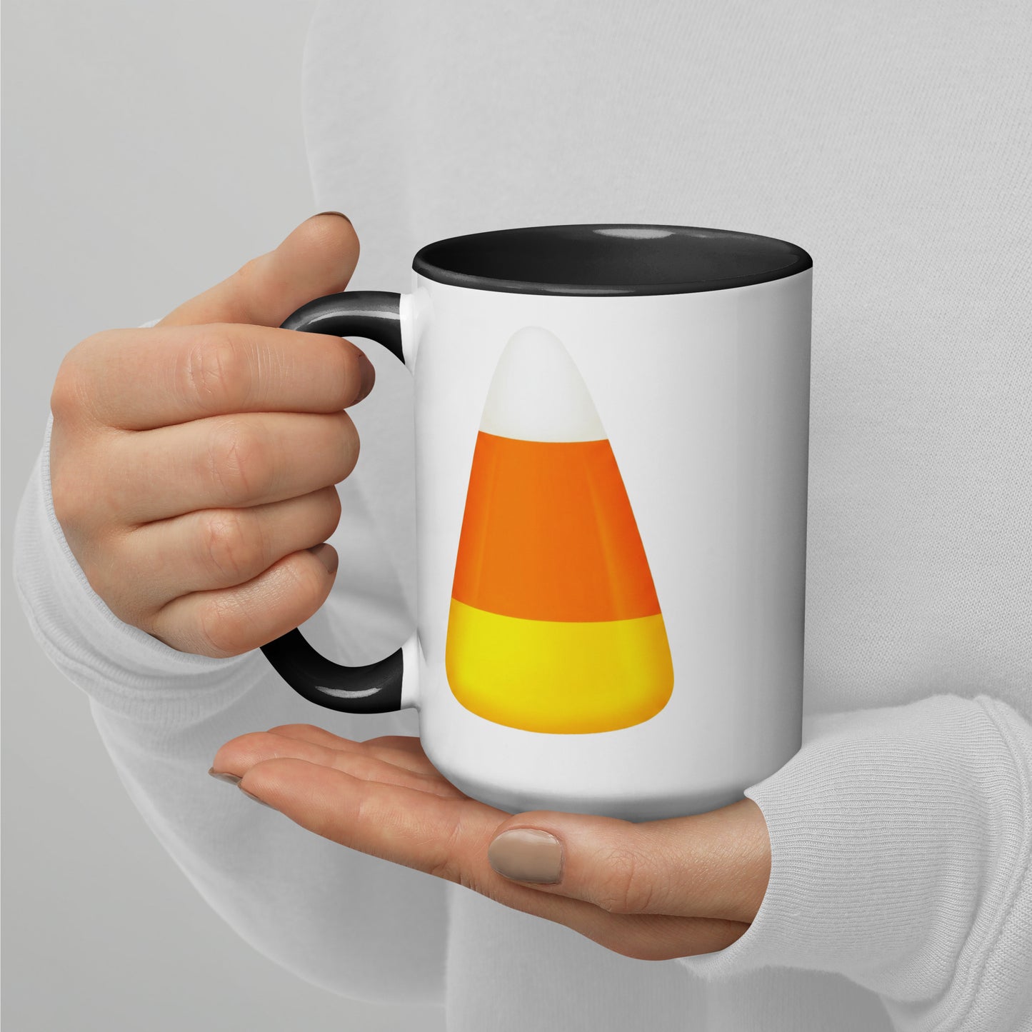 White ceramic mug with a black handle and black interior. Halloween candy corn design in white, orange, and yellow.