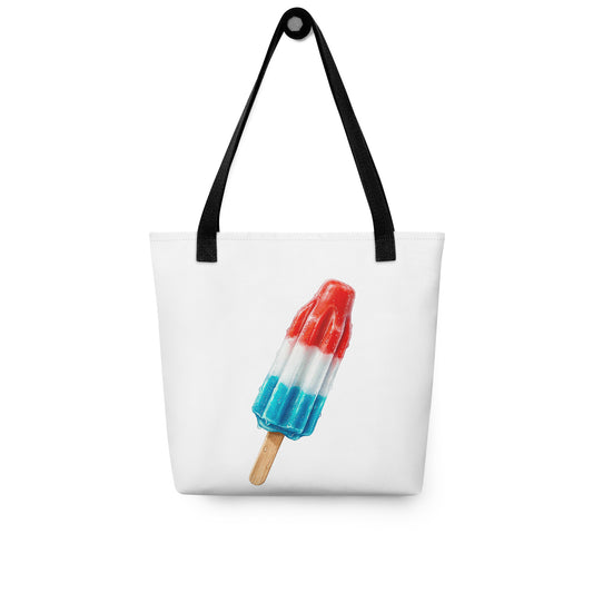 A white tote bag with black shoulder straps, a fun summer graphic of a red, white, and blue popsicle