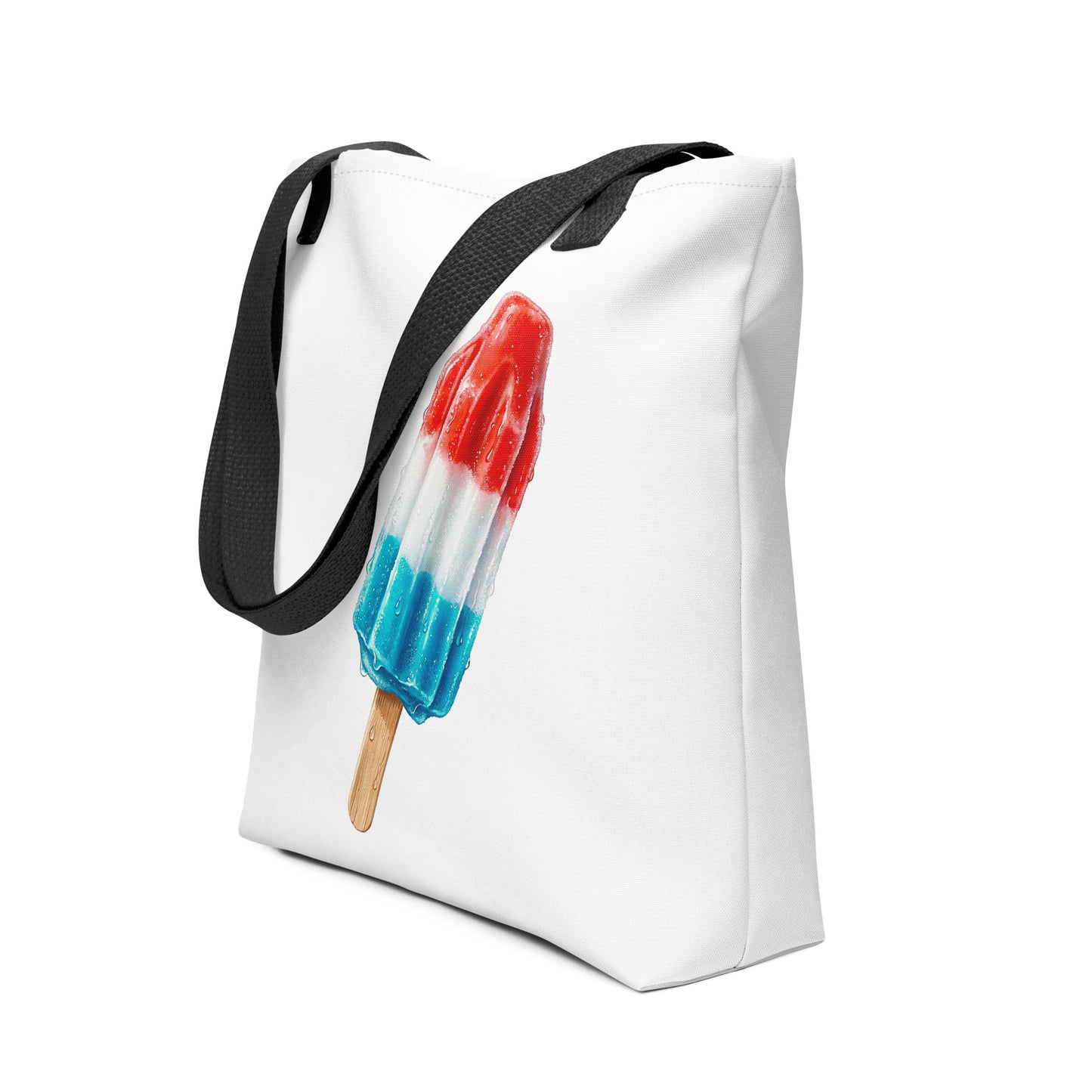 A white tote bag with black shoulder straps, featuring a printed graphic of a red, white, and blue popsicle